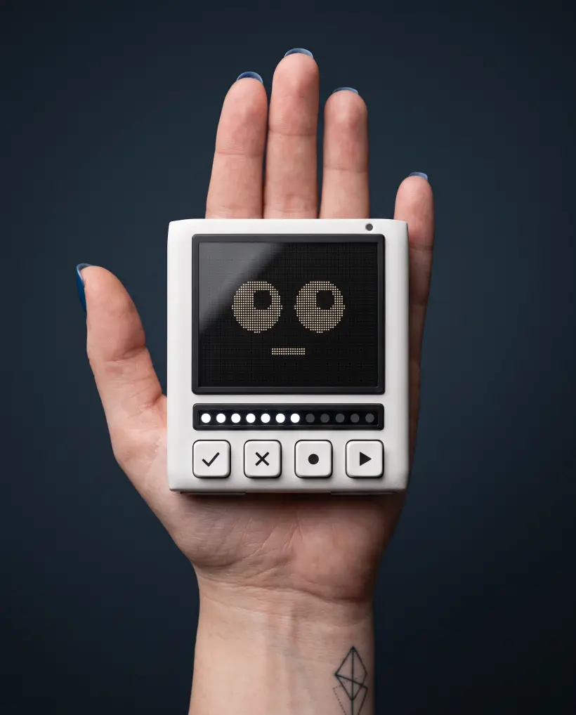 The Pixli lying flat on an open palm, its dot-matrix face lit